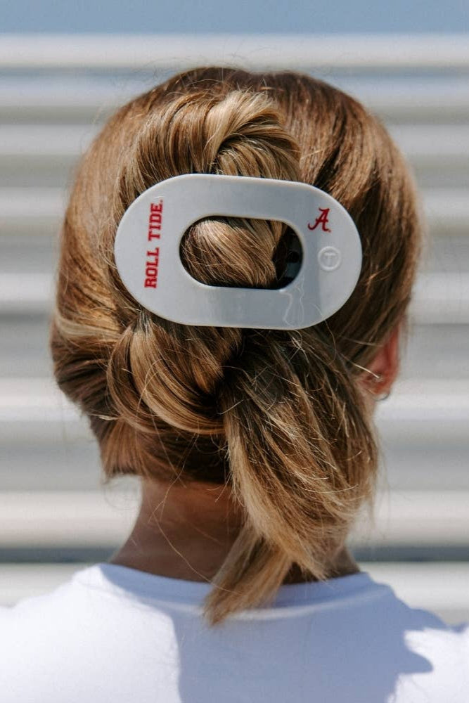Person with braided hair wearing a hair tie with 'Roll Tide' and 'A' branding.