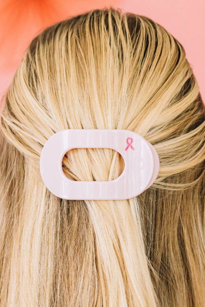 Blonde hair with a white hair clip featuring a pink ribbon on a pink background