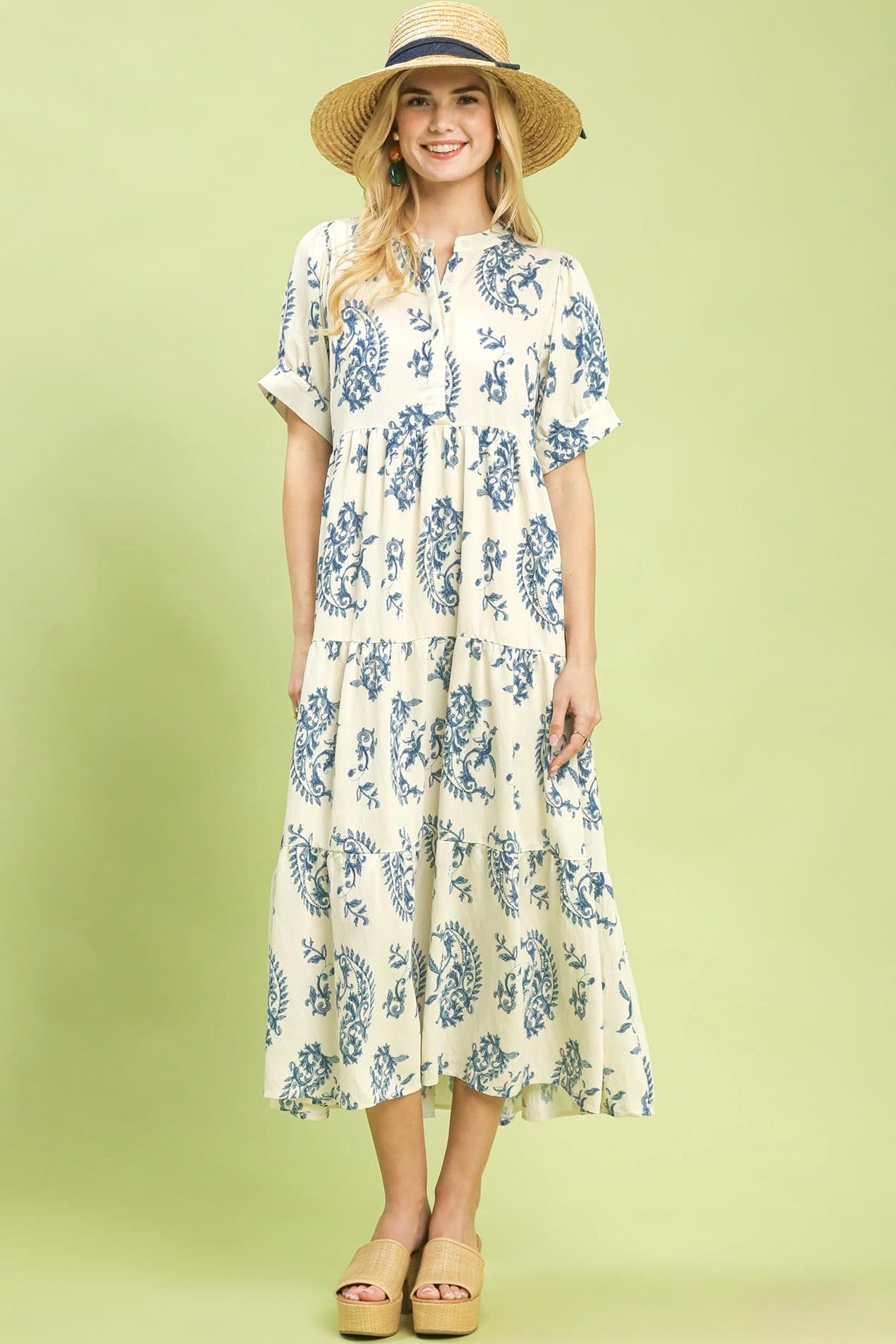 Woman wearing a floral dress and straw hat on a light green background