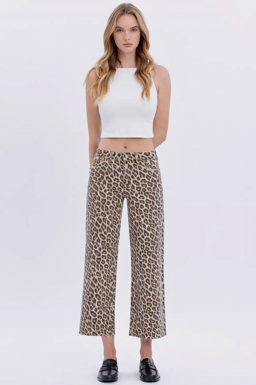 Woman wearing a white top and leopard print pants on a white background