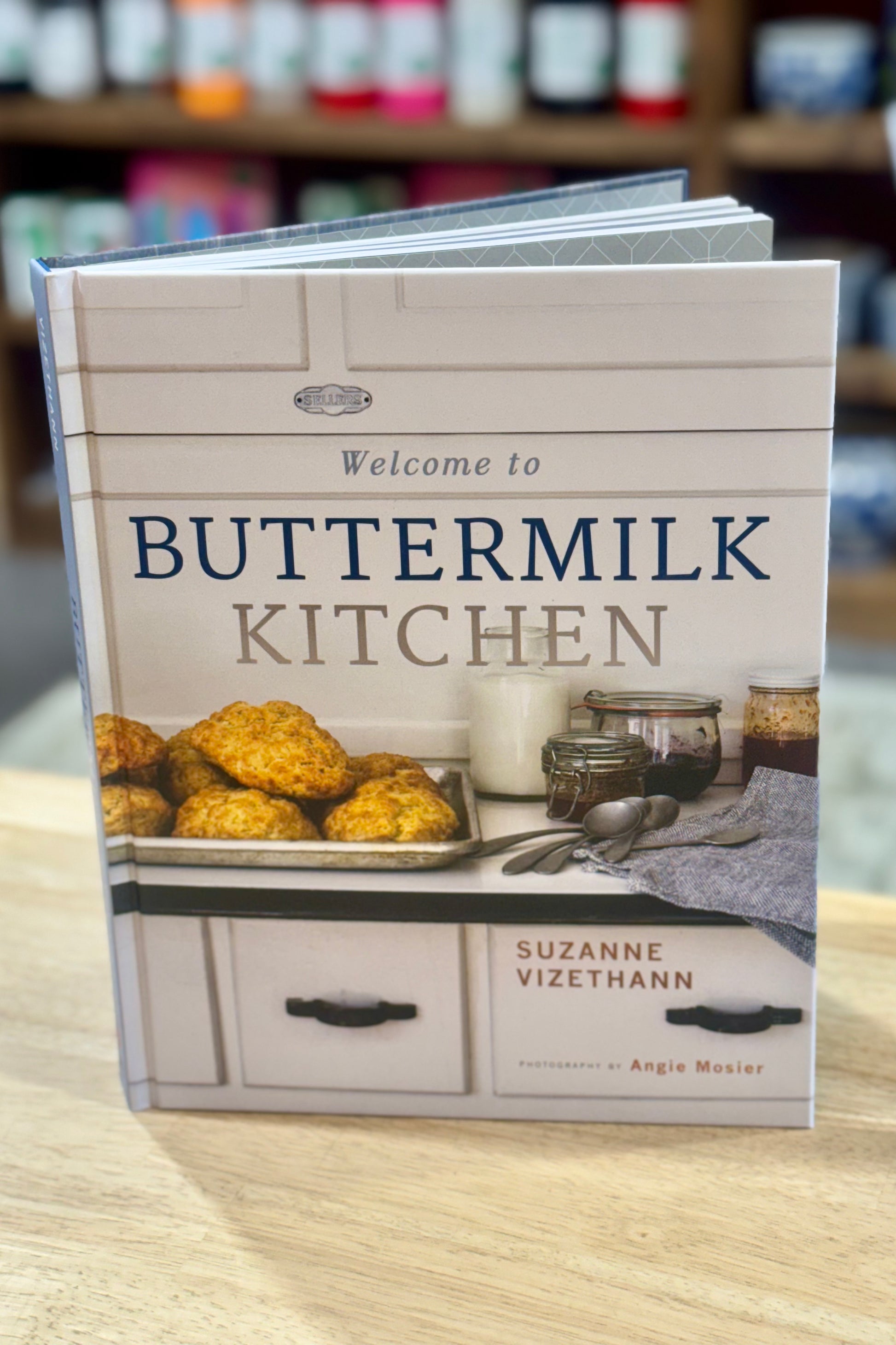 Book titled 'Buttermilk Kitchen' by Suzanne Vizethann on a wooden surface with blurred background