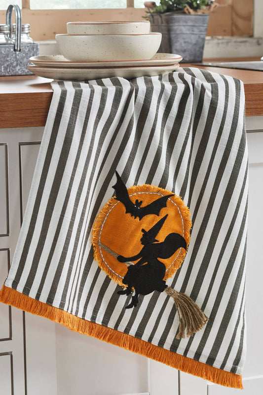 Halloween-themed kitchen towel with black and white stripes and a witch design on a kitchen counter.