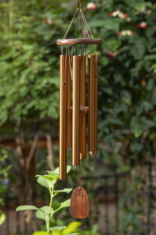 Bronze wind chime hanging among greenery