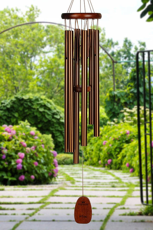 bronze Wind chime hanging in a garden with greenery and flowers
