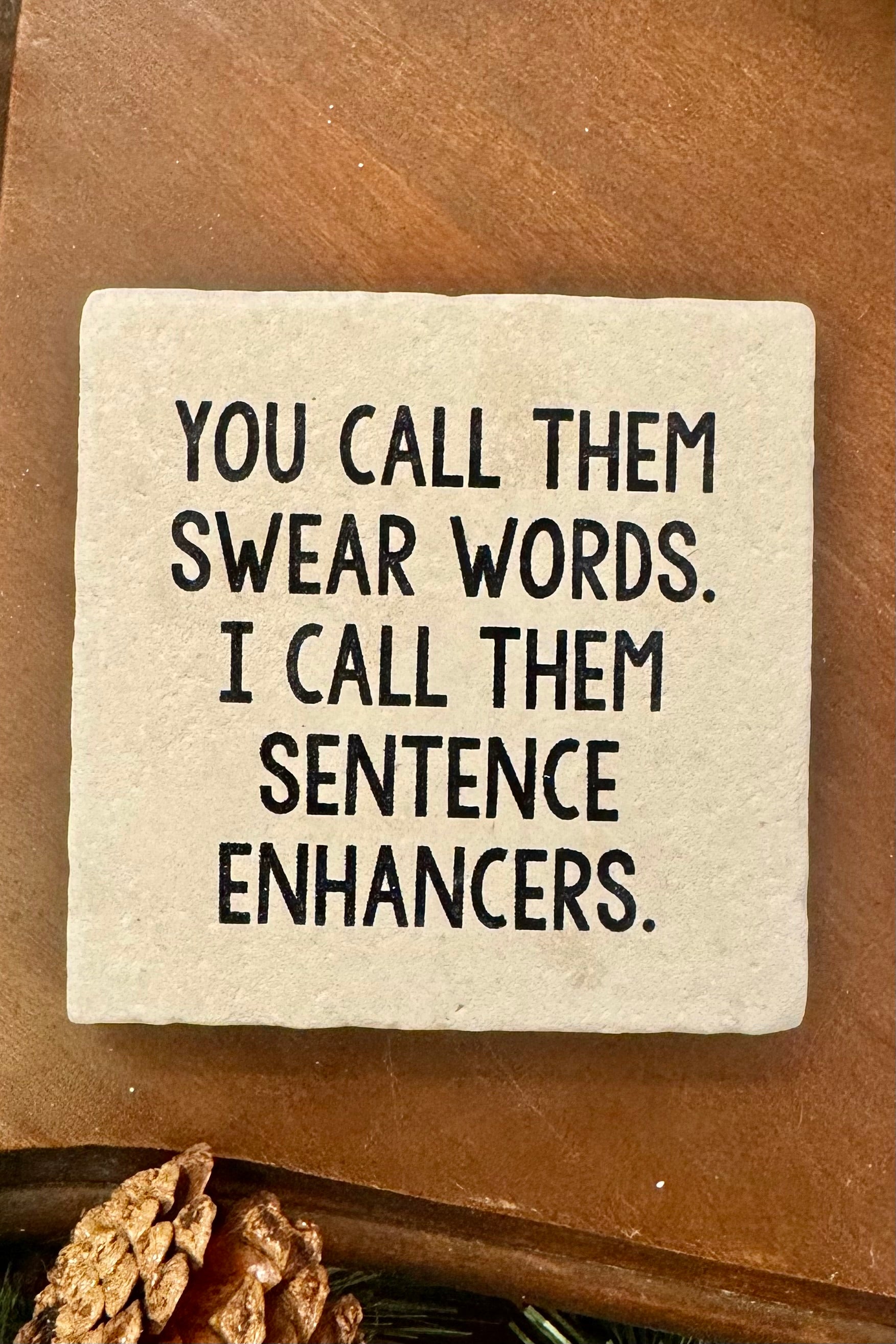 Square stone coaster with humorous text on a wooden surface