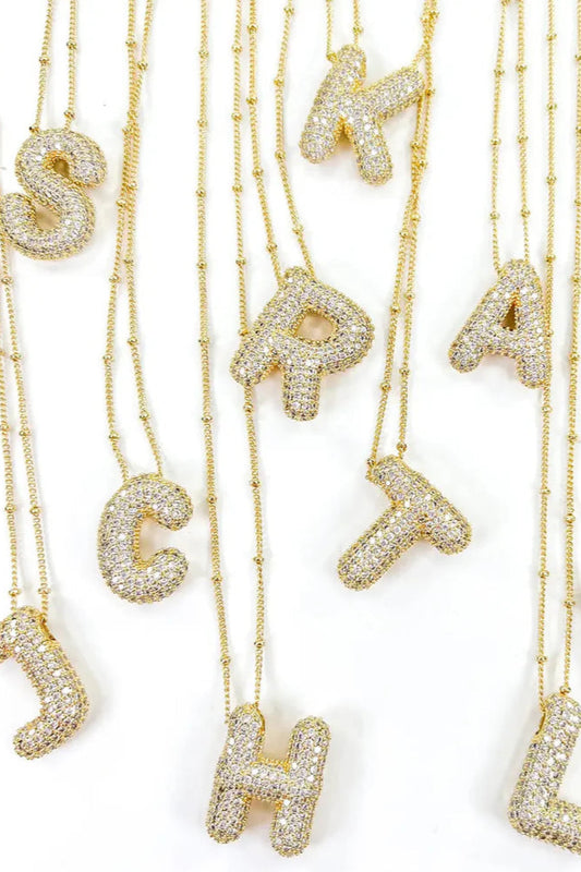 Gold necklaces with letter pendants on a white background