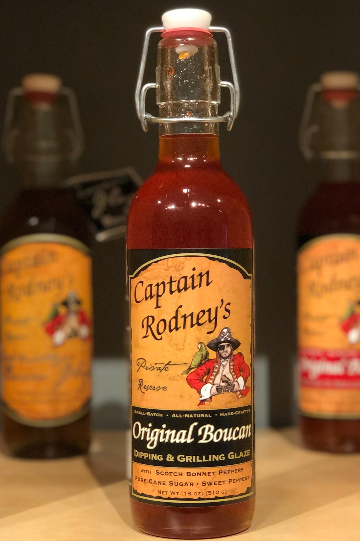 Bottle of Captain Rodney's Original Boucan Dipping & Grilling Glaze with two other bottles in the background.