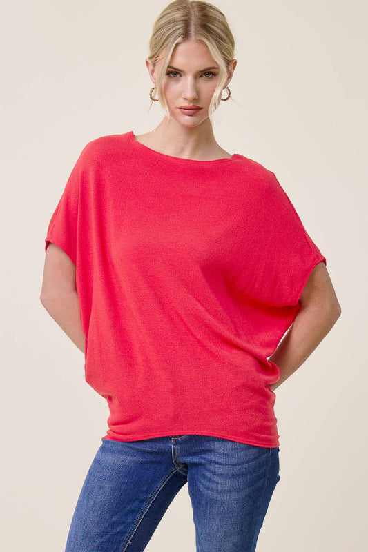 Woman wearing a bright red top and blue jeans on a beige background