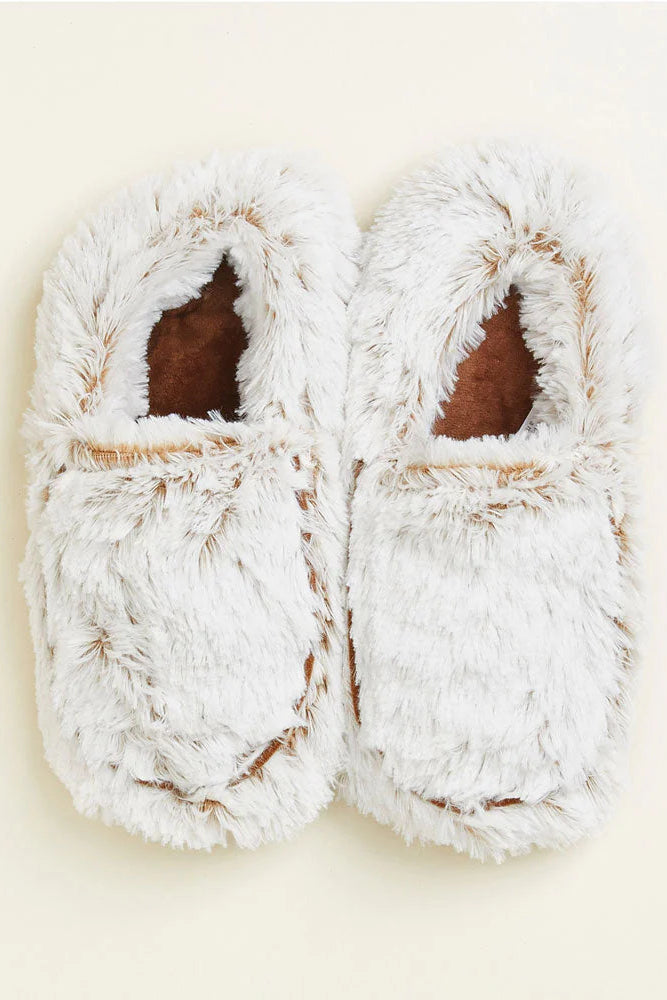 Pair of white fuzzy slippers on a beige background