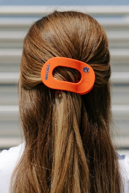 Person with orange Auburn hair clip featuring a logo in a stadium setting